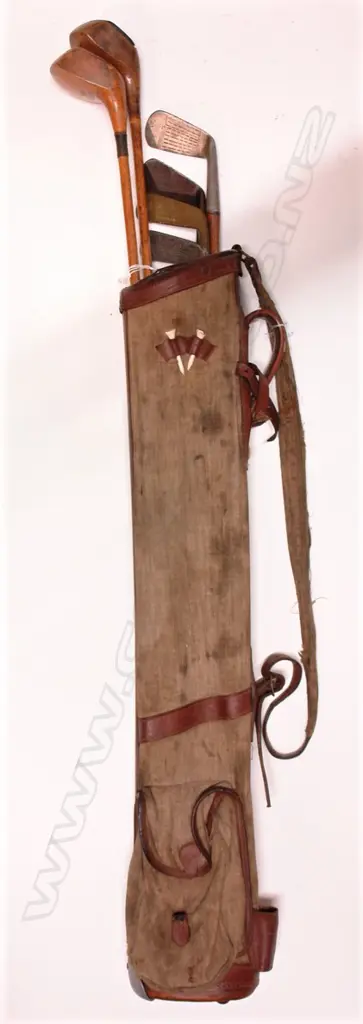 An old canvas and leather stitched trim golf bag with a collection of six hickory shafted clubs Image 1++