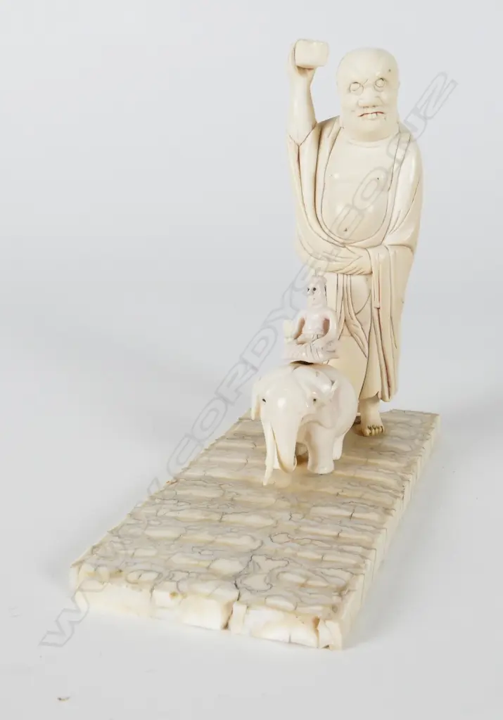 A carved ivory standing figure holding shoe Image 1++