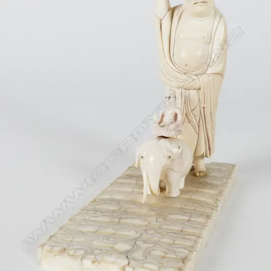 A carved ivory standing figure holding shoe