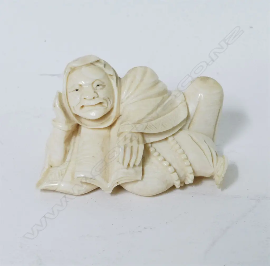 A carved ivory okimono of a reclining man reading a book Image 1++