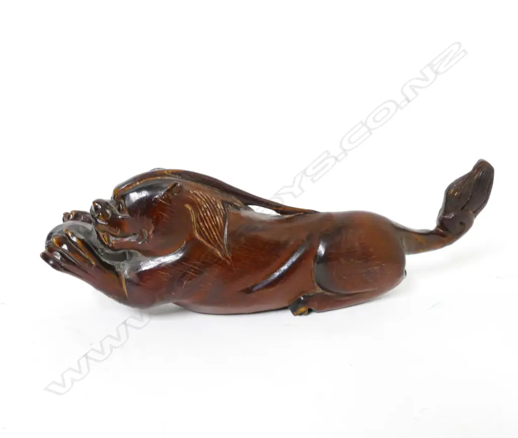 A carved wood or horn recumbent lion Image 1++