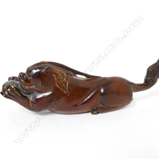 A carved wood or horn recumbent lion